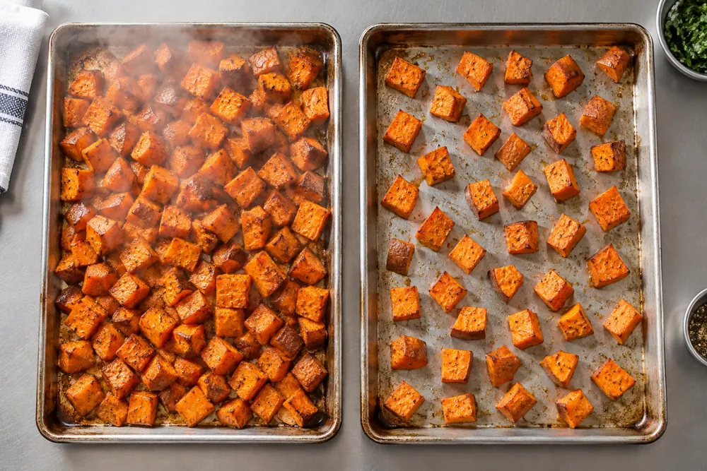 Crowded and spaced pans of sweet potato cubes